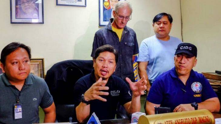 Alleged Australian sex offender Peter Gerard Scully stands behind Philippines police investigator Angelito Magno. Photo: Bobby Lagsa/Inquirer Mindanao