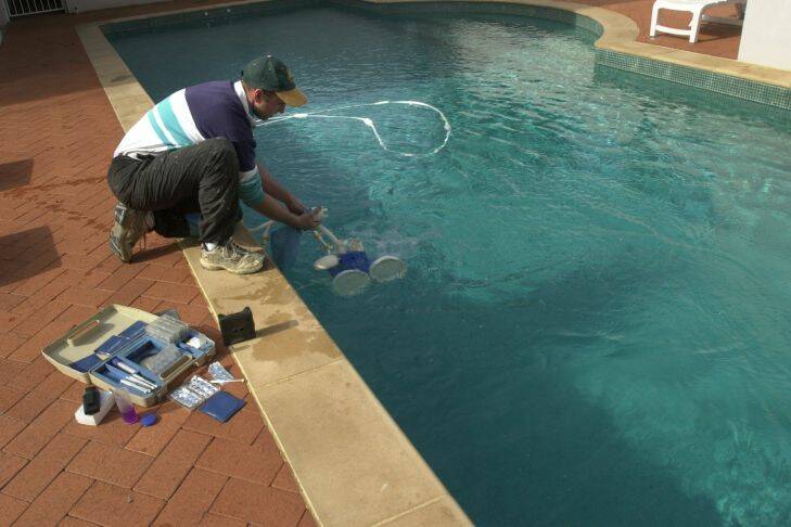 Richard Briggs pic......1aug03......Canberra Pools owner Brad  Garbutt  cleans and checks the water quality of a pool in Red Hill as possible severe water restrictions threaten pool levels..........Story-                                                            