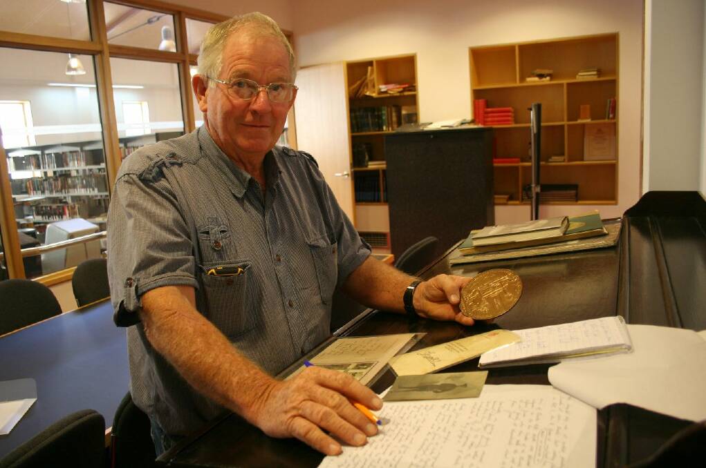 Junee farmer Graham Elphick looks over the records of Private Charles John Mills, a Junee man killed in WWI, including a bronze medallion known as the “dead man’s penny” which was given to Commonwealth soldiers. Picture: Declan Rurenga