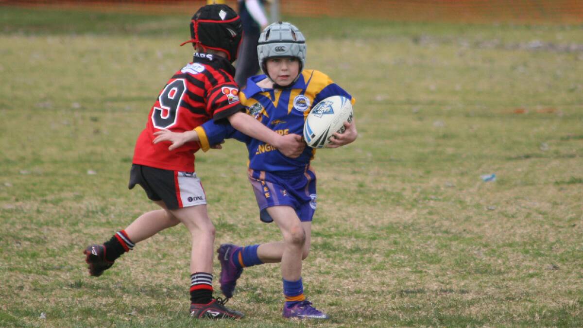 Alex McGregor tries to fend the North Canberra Bears player off in Under 6-7s.