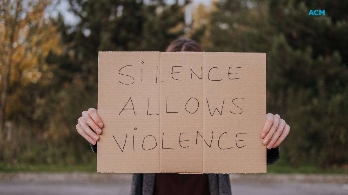 Stock image of a woman holding a sign reading 'silence allows violence'. Picture Canva