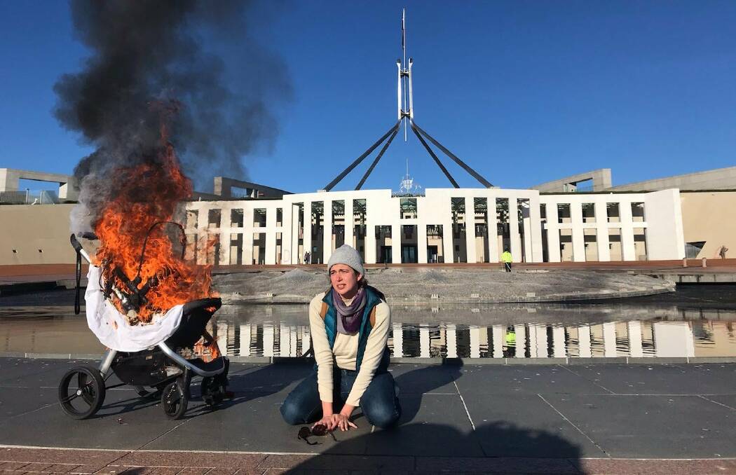 Extinction Rebellion member Deanna Marie "Violet" Coco beside a burning pram outside Parliament House. Picture: Supplied