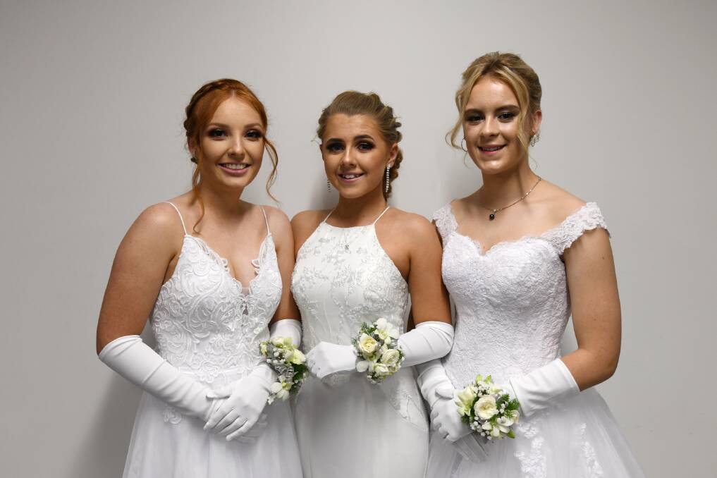 STUNNING IN WHITE: Eilee Philipse, Taylah Hackett and Jasmine Phillips arrive for the evening's procession of debutantes.