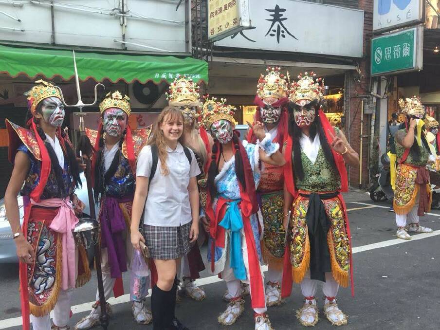 CULTURAL EXPERIENCE: Jasmine Phillips (centre) dressed in her formal school uniform during a festival parade in Taipai. The performers are dressed in the traditional 'face of the gods'. Picture: supplied