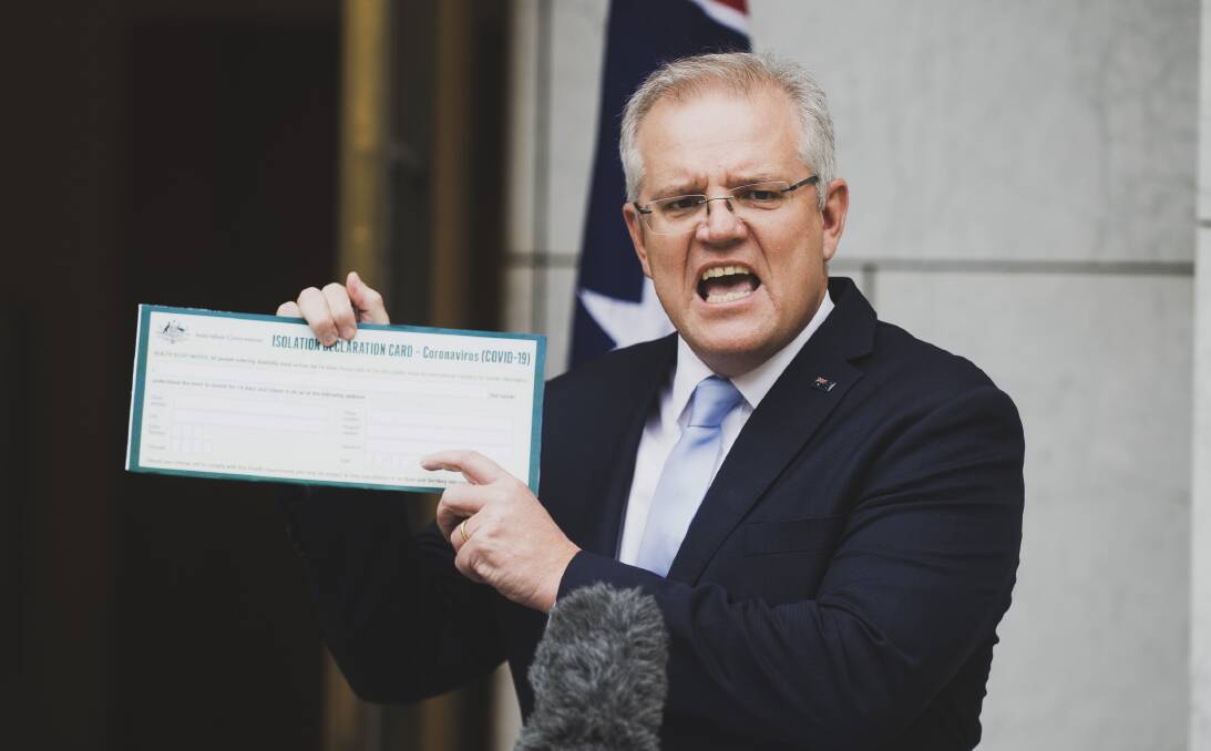 Prime Minister Scott Morrison on Friday with a version of the coronavirus quarantine declaration that all international arrivals must sign. Picture: Dion Georgopoulos