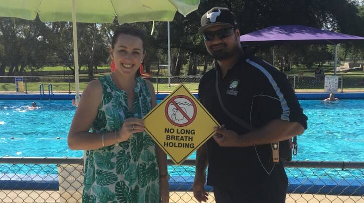 SAFETY FIRST: Meg Norrie (left) hands over a donated safety sign encouraging swimmers not to hold their breath for too long underwater. 